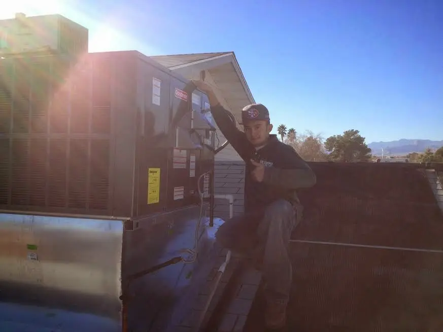HVAC technician performing Heat Pump Repair on a rooftop unit in Stowe